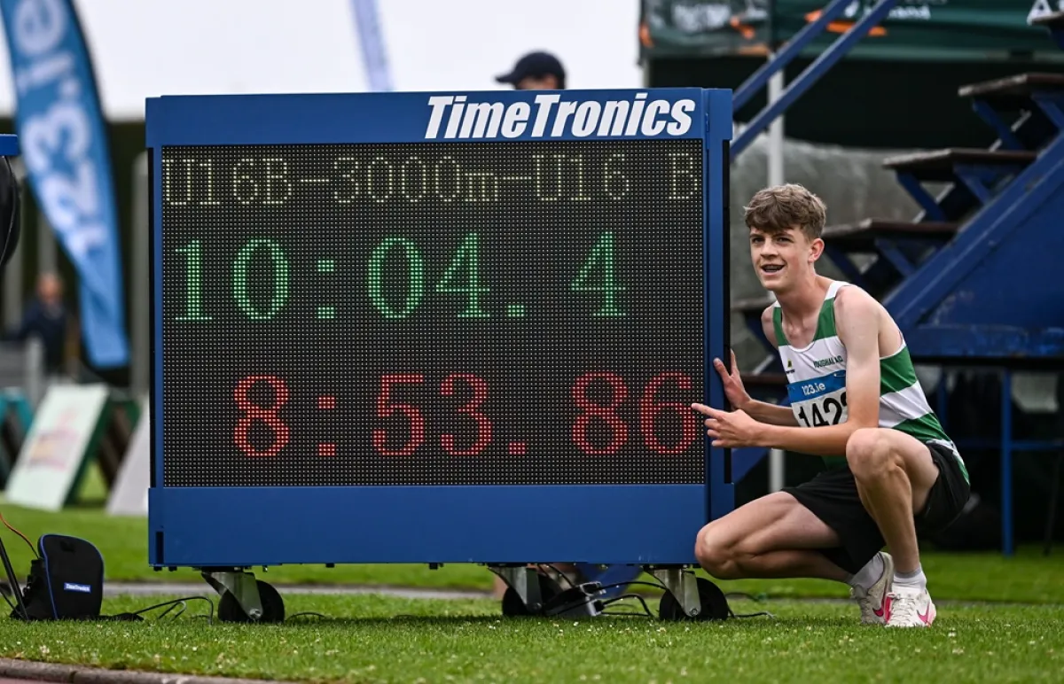 Photo of juveniles athlete posing beside timing clock